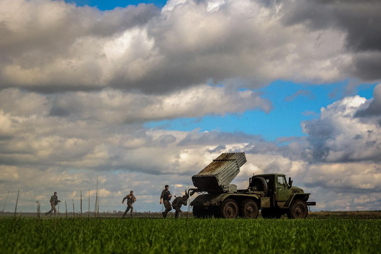 Ukrainische Soldaten in der Region Donezk im Osten des Landes laufen auf freiem Feld zu einem Raketenwerfer.