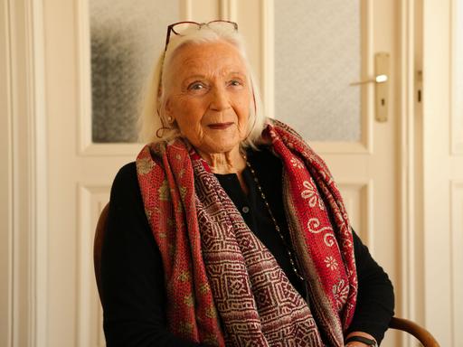 Die Autorin Gabriele von Arnim ist weißhaarig und trägt einen roten Schal. 













