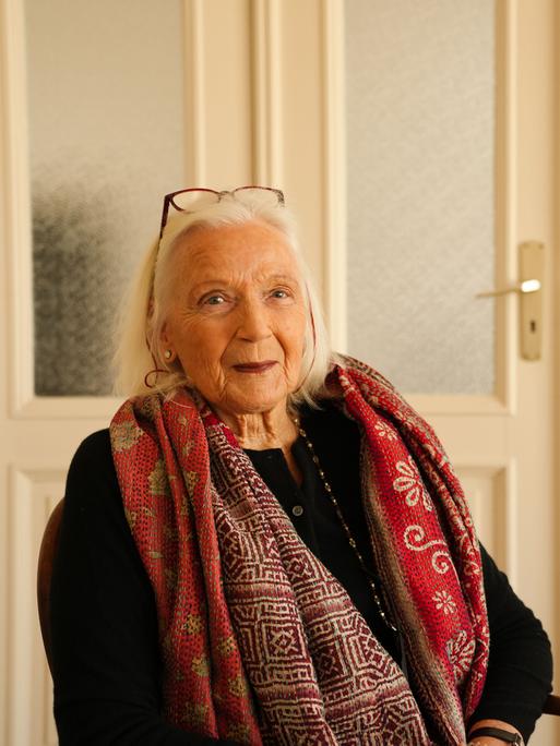 Die Autorin Gabriele von Arnim ist weißhaarig und trägt einen roten Schal. 













