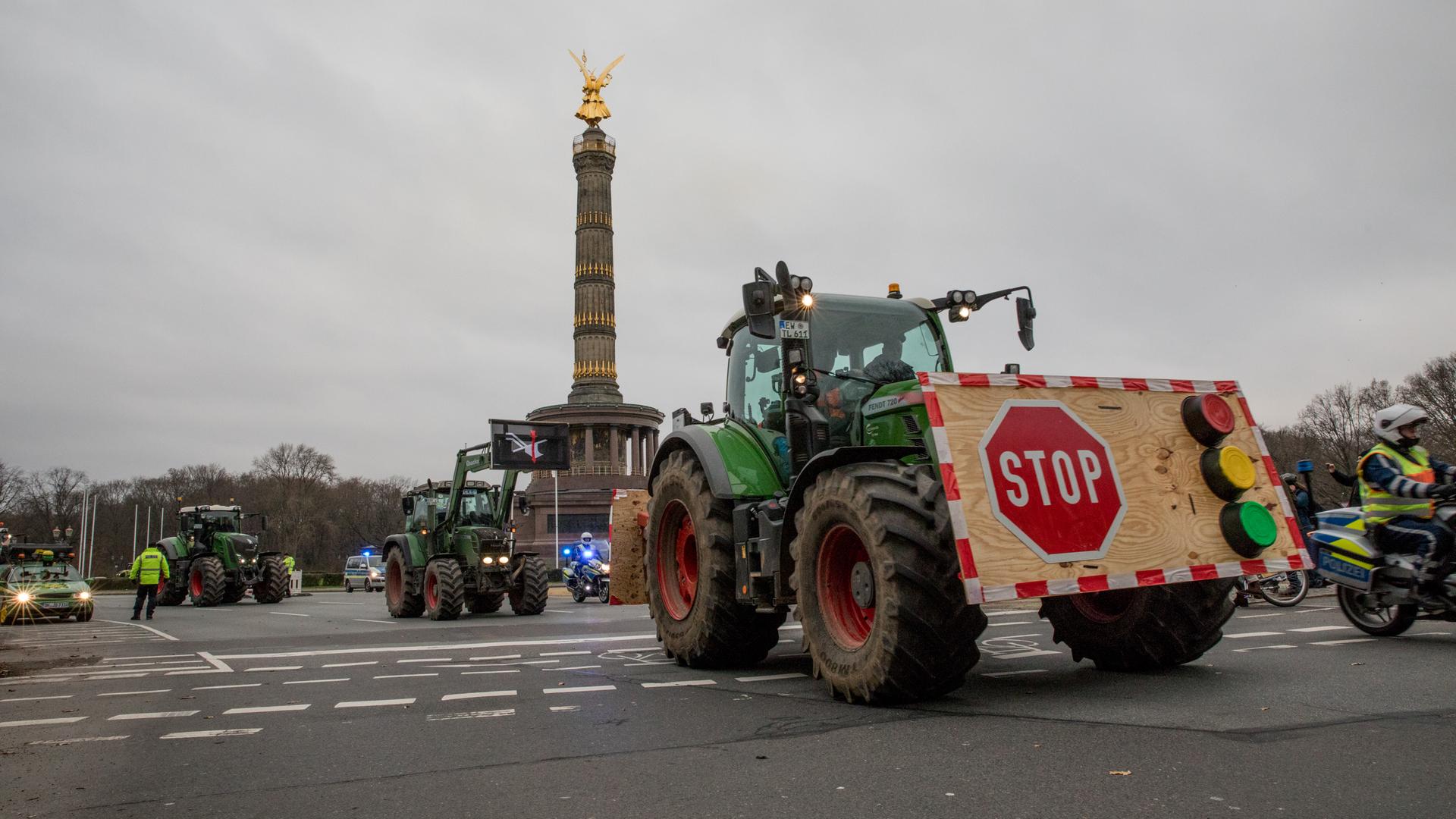 Mehrere Traktoren bei einer Protestaktion der Bauern an der Siegessäule in Berlin, begleitet von Polizei.