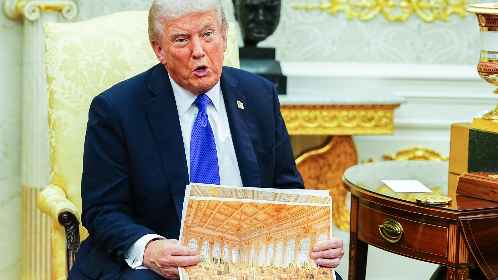 US-Präsident Donald Trump hält ein Foto hoch, dass den goldenen Ballsaal zeigt, den er im Weißen Haus gerade bauen lässt. US-Präsident Donald Trump hält ein Foto hoch, dass den goldenen Ballsaal zeigt, den er im Weißen Haus gerade bauen lässt.