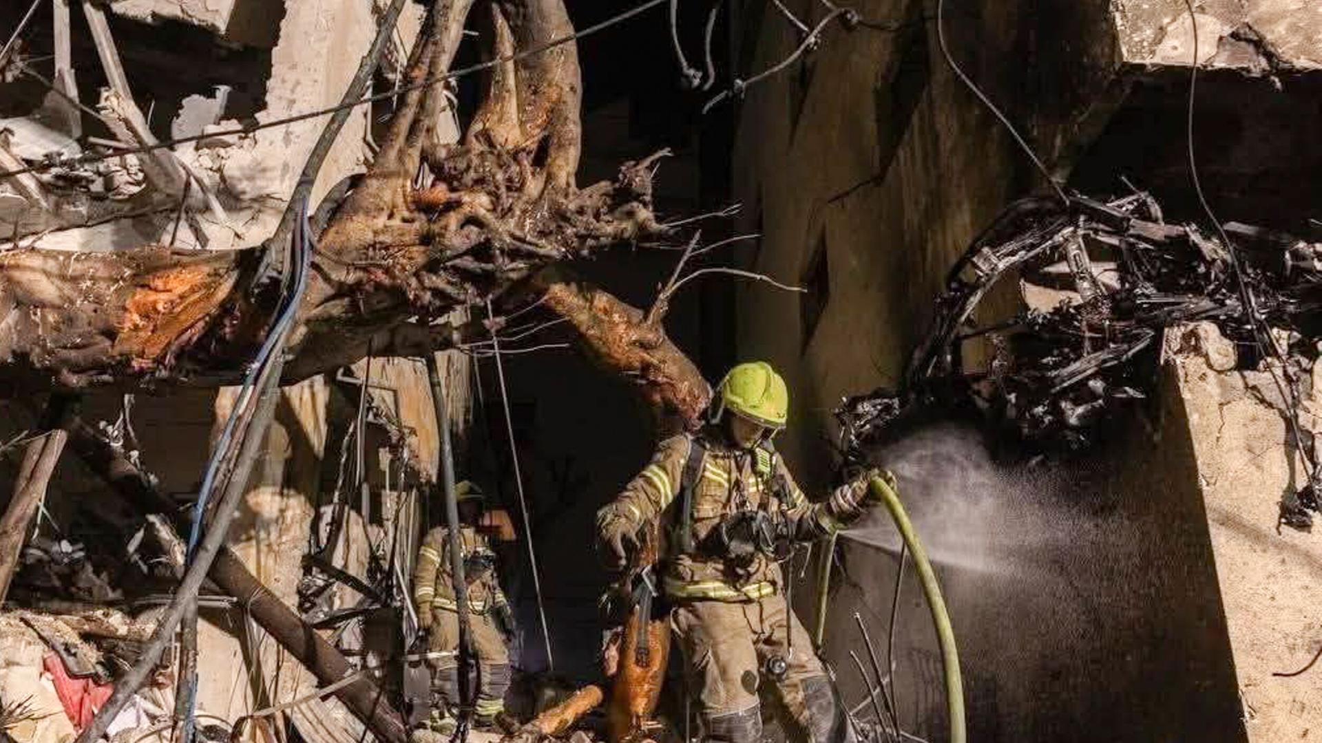Ein Feuerwehrmann versucht, in einem zerstörten Haus Feuer zu löschen.
