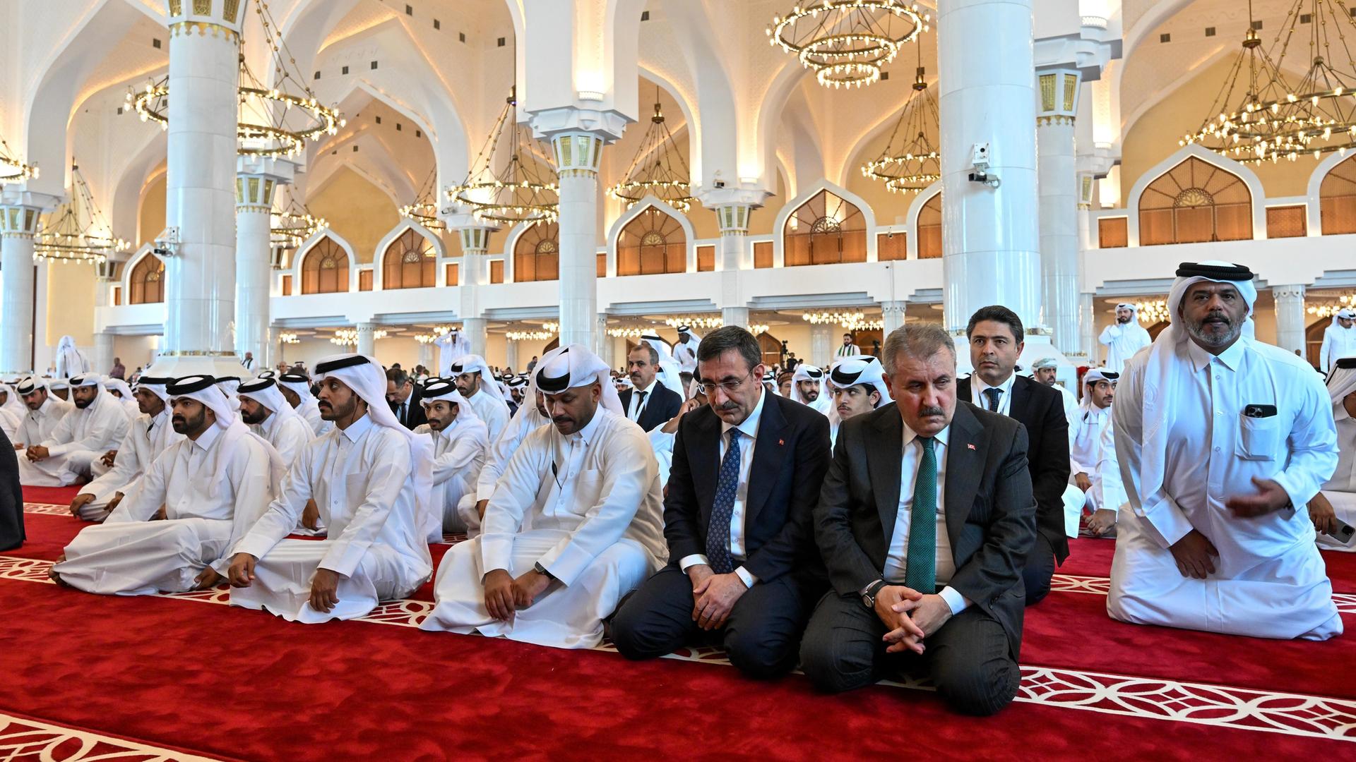 Männer knien zum Gebet auf dem Boden einer Moschee in Doha.