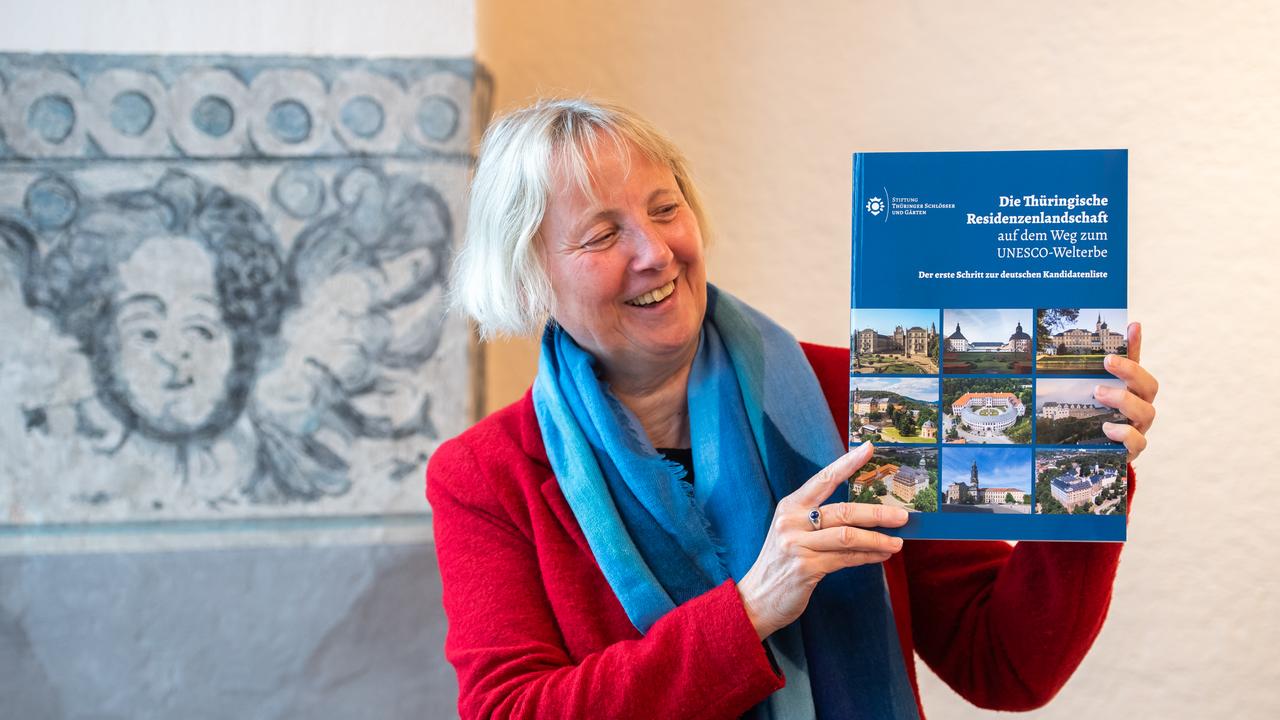 Eine Frau hält ein Buch hoch mit dem Titel "Die Thüringische Residenzenlandschaft" 