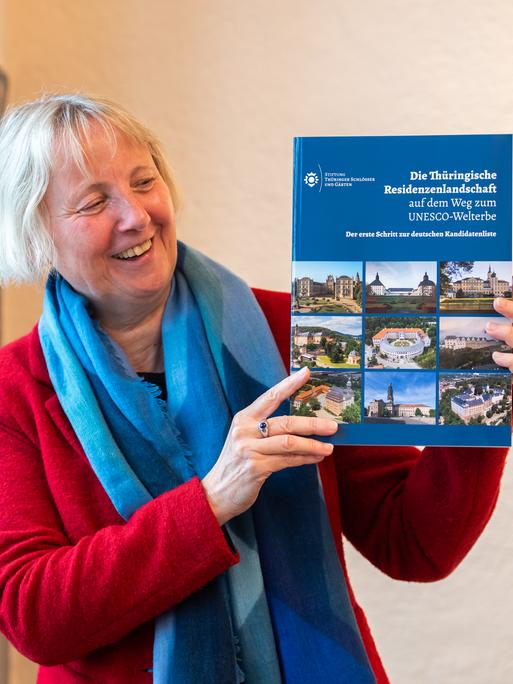 Eine Frau hält ein Buch hoch mit dem Titel "Die Thüringische Residenzenlandschaft" 