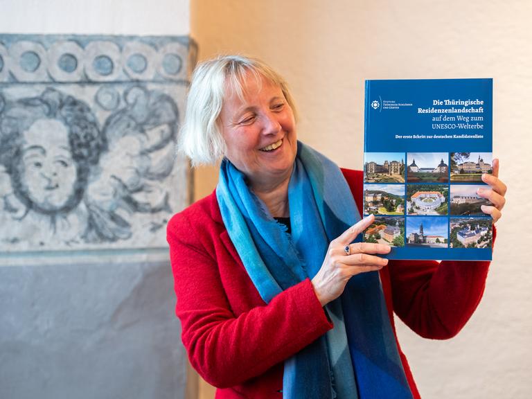 Eine Frau hält ein Buch hoch mit dem Titel "Die Thüringische Residenzenlandschaft" 