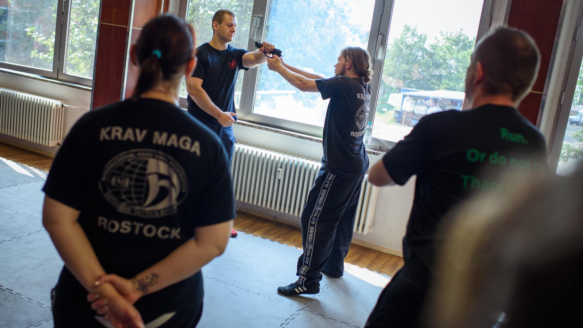Der Seminarleiter Lars van Schaik (l.) zeigt den Teilnehmern eines Seminares zur Selbstverteidigungstechnik Krav Maga in Potsdam eine Technik zur Entwaffnung des Gegners.