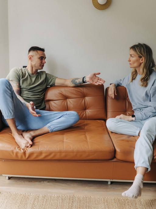 Ein Mann und eine Frau diskutieren auf einer Couch Ein Mann und eine Frau diskutieren auf einer Couch