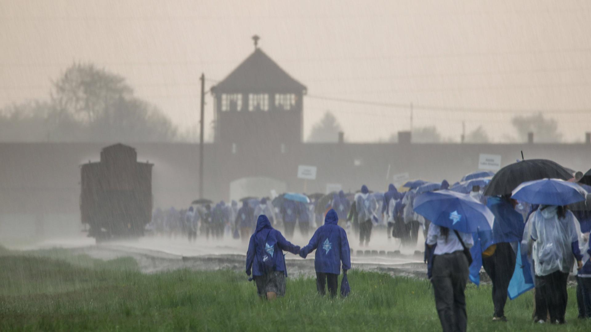 Das ehemalige Konzentrationslager Ausschwitz wird von heftigem Niederschlag heimgesucht. Auf dem Bild sind mehrere junge Leute zu sehen, die dem KZ einen Besuch abstatten. Das ehemalige Konzentrationslager Ausschwitz wird von heftigem Niederschlag heimgesucht. Auf dem Bild sind mehrere junge Leute zu sehen, die dem KZ einen Besuch abstatten.