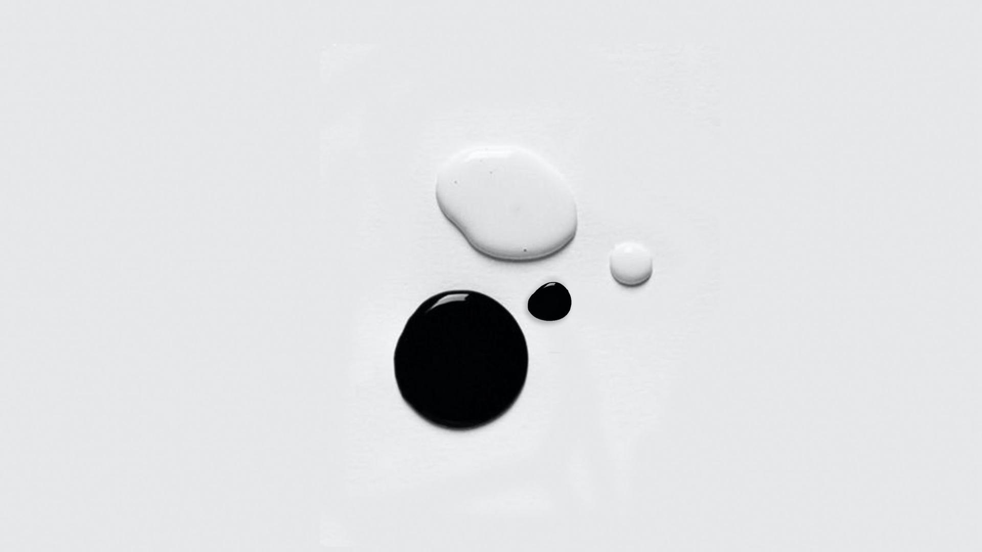 Zwei Farbkleckse, einer schwarz der andere weiß, liegen auf einem hellen Grund auf.