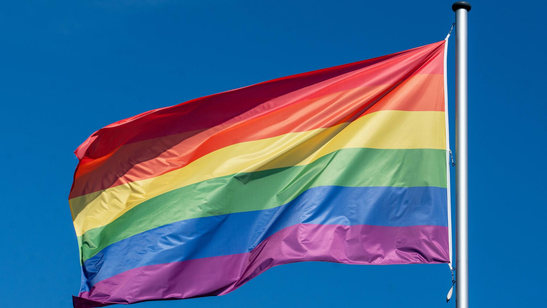 Eine Regenbogenflagge weht im Wind.