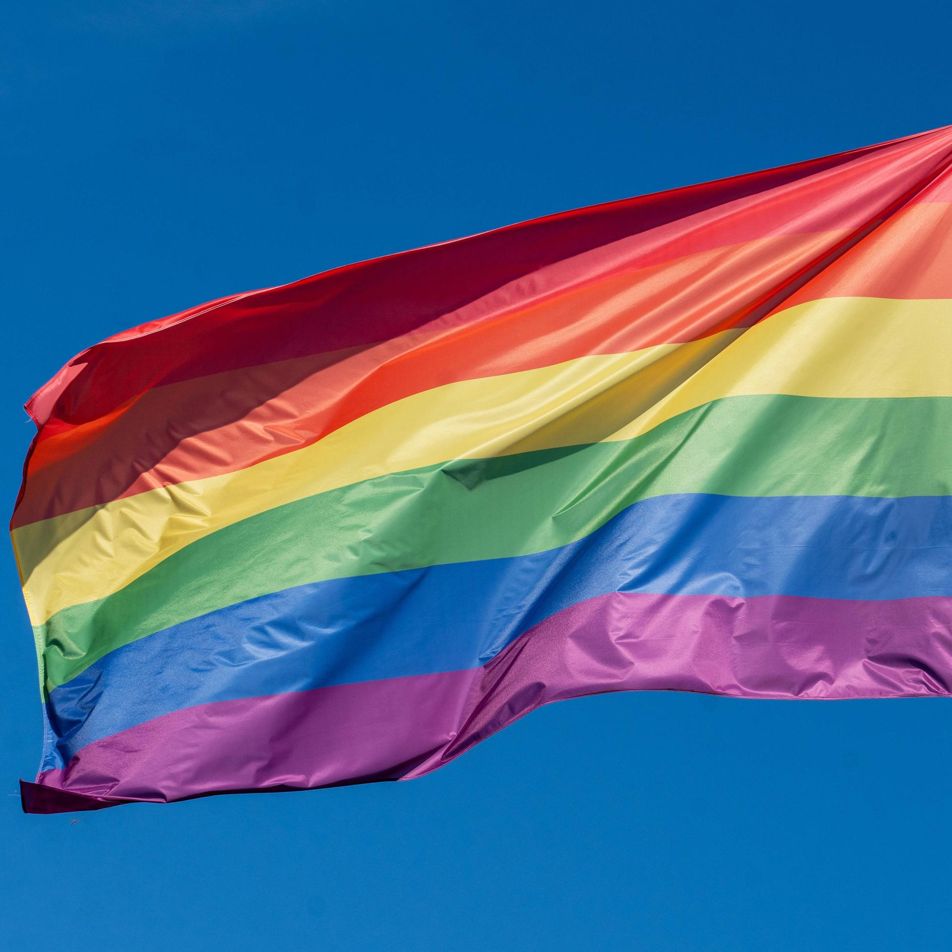 Regenbogenflagge weht im Wind.