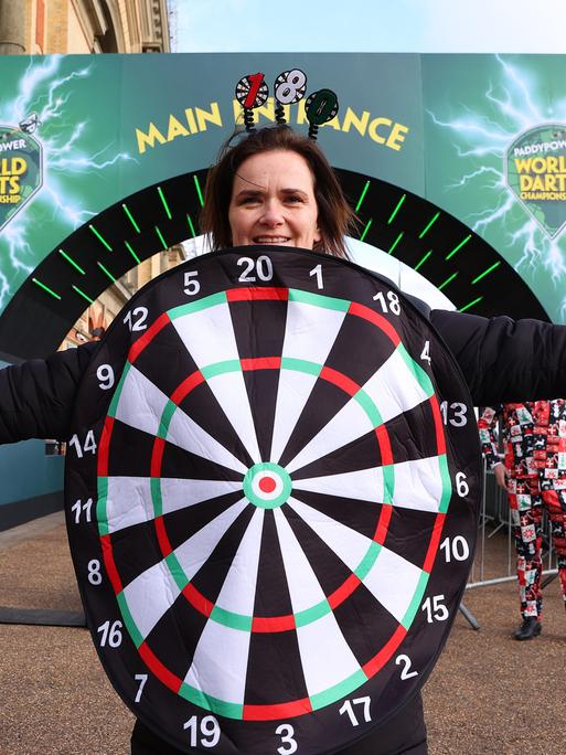 Ein als Dartscheibe verkleideter weiblicher Darts-Fan posiert vor dem Alexandra Palace in London. 