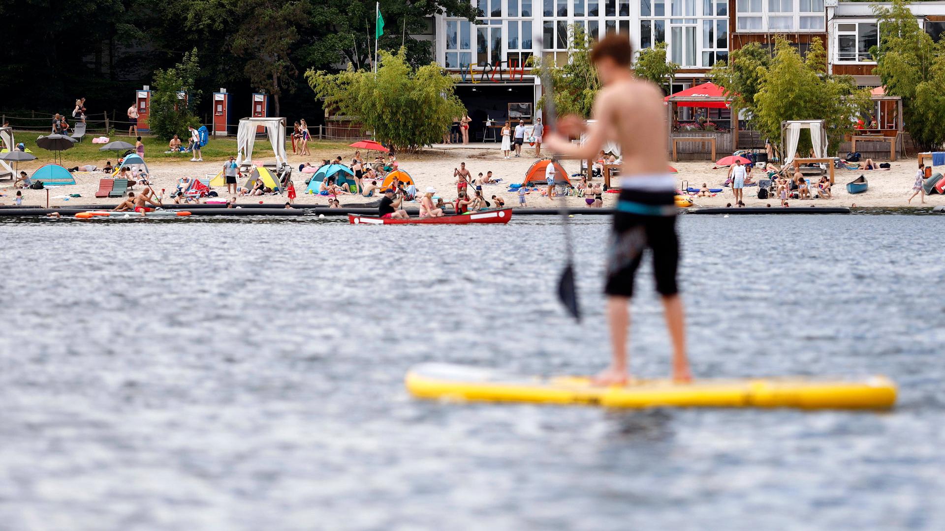 Auf einem See steht ein Junge auf einem Stand-Up-Paddle-Board.