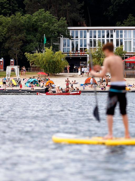 Auf einem See steht ein Junge auf einem Stand-Up-Paddle-Board.