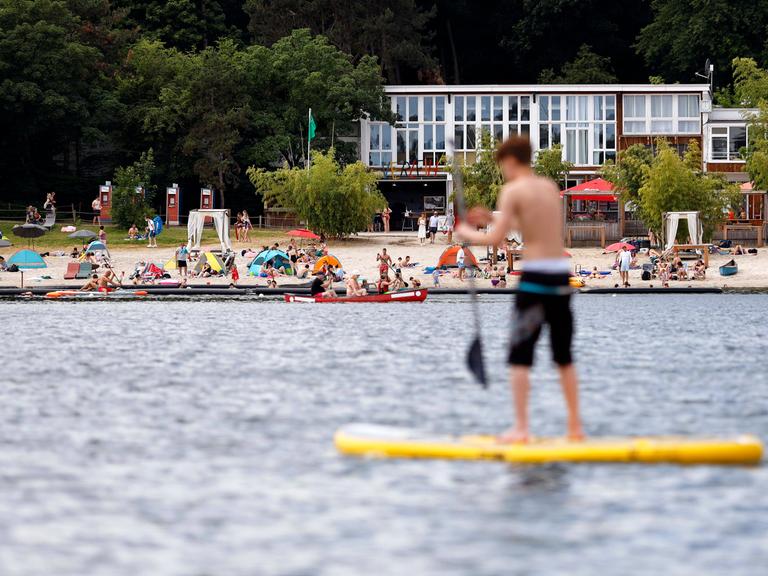 Auf einem See steht ein Junge auf einem Stand-Up-Paddle-Board.