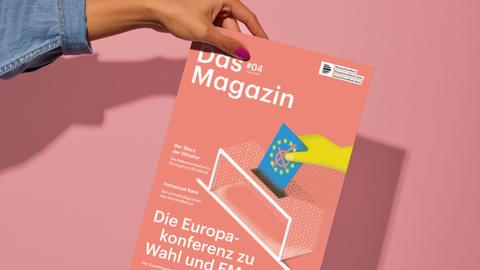 Eine weibliche Hand hält die April-Ausgabe des Deutschlandfunk Magazins vor einer pastellrosafarbenen Wand