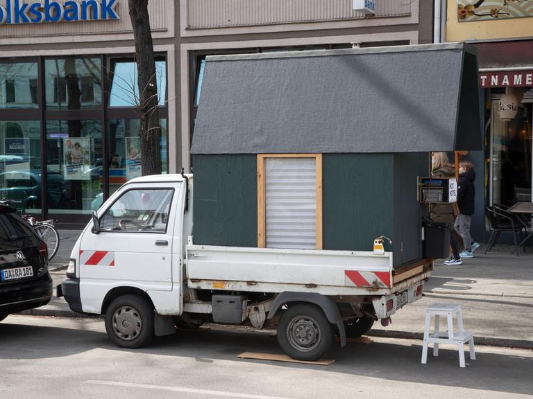 Ein Transporter auf dessen Ladefläche ein kleines Holzhaus steht