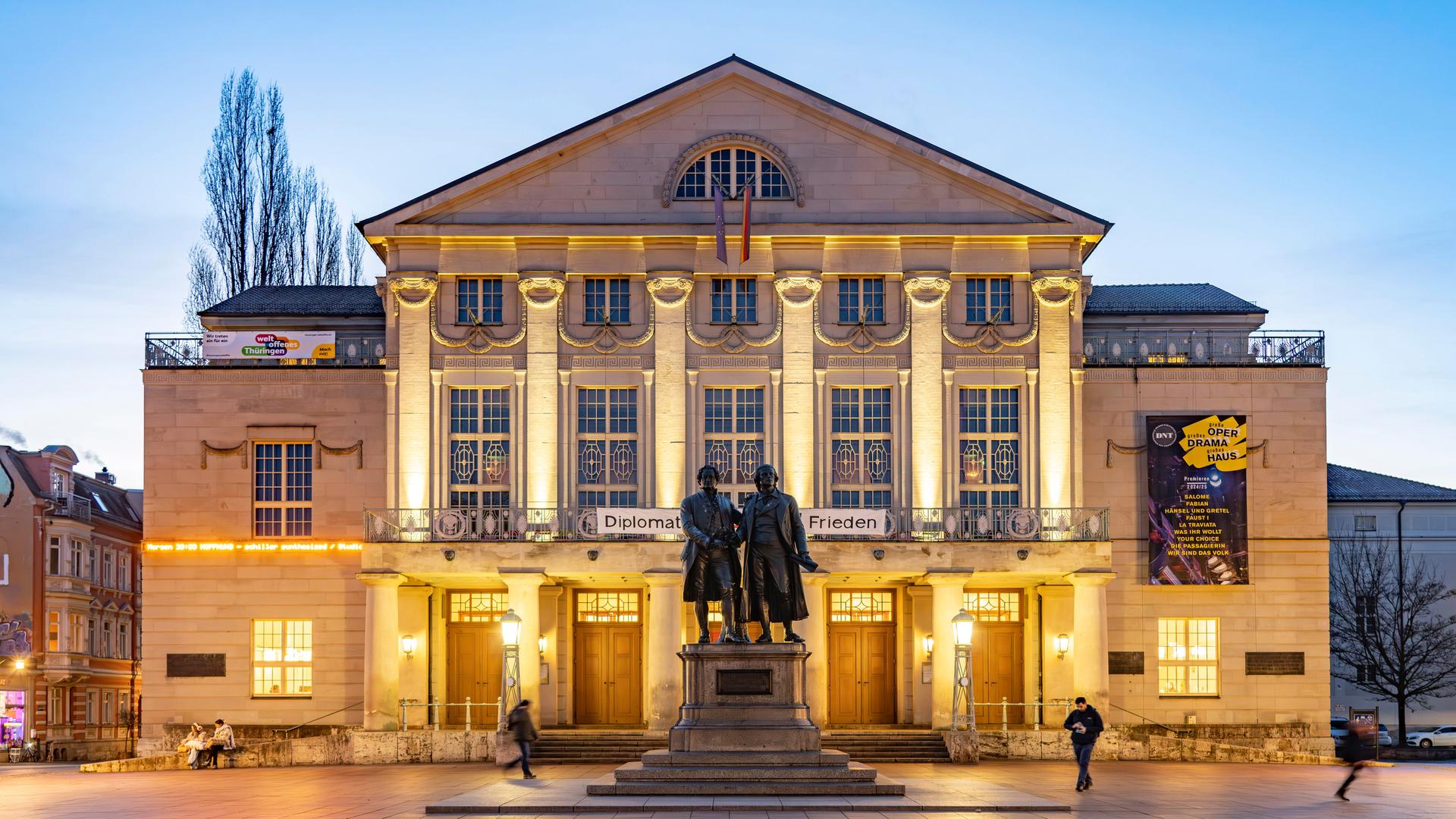 Das Deutsche Nationaltheater mit dem Goethe-und-Schiller-Denkmal in der Abenddämmerung.