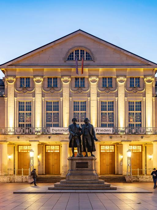 Das Deutsche Nationaltheater mit dem Goethe-und-Schiller-Denkmal in der Abenddämmerung.