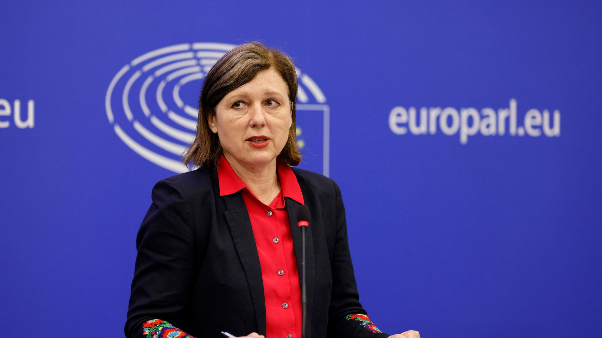Jourova spricht vor einer blauen Wabd mit dem weißen Logo des Europaparlaments und der weißen Schrift "europarl.eu".