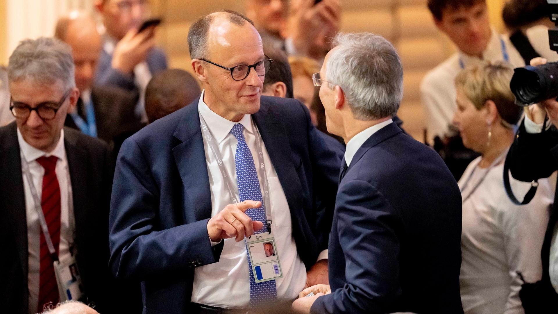 Der Kanzlerkandidat der Union, Friedrich Merz, steht bei der Sicherheitskonferenz in München in einer Gruppe von Menschen und unterhält sich.