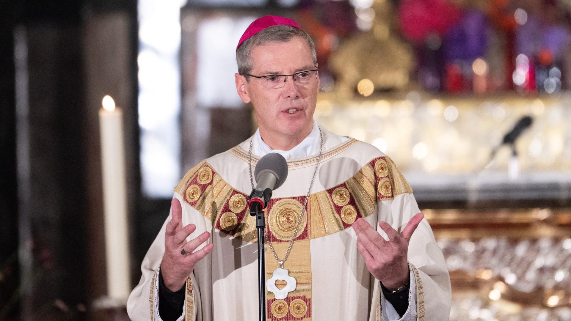 Bischof Wilmer hält beim Eröffnungsgottesdienst eine Predigt. Er steht hinter einem Mikrofon und gestikuliert.