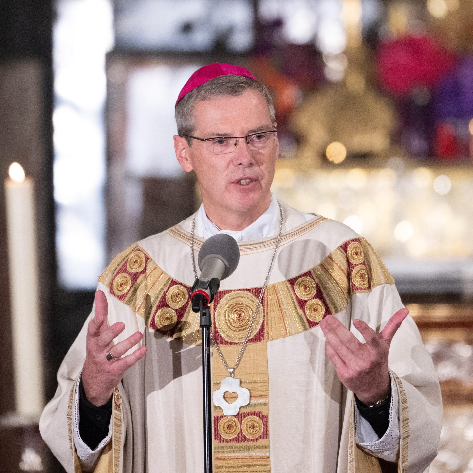 Bischof Wilmer hält beim Eröffnungsgottesdienst eine Predigt. Er steht hinter einem Mikrofon und gestikuliert.