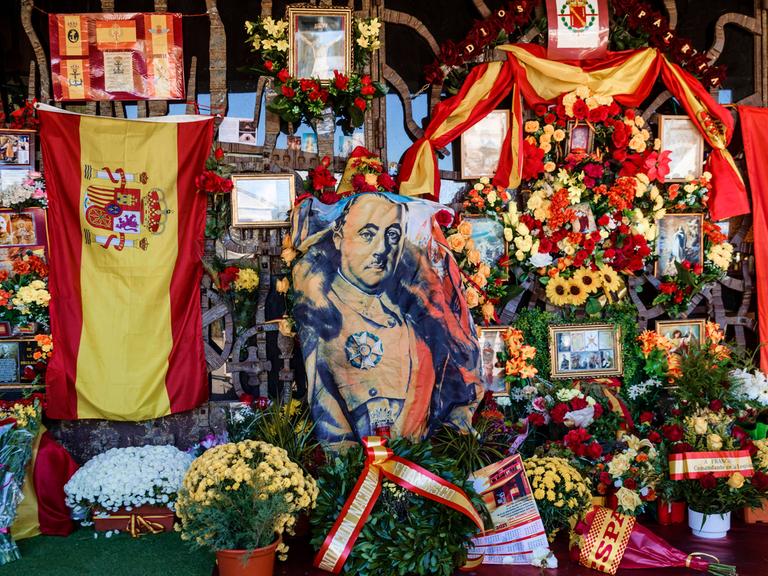 Grabmal des Diktators Francisco Franco auf dem Friedhof von Mingorrubio-El Pardo in Madrid, umsäumt von spanischen Flaggen, Blumen und Gedenkkarten.