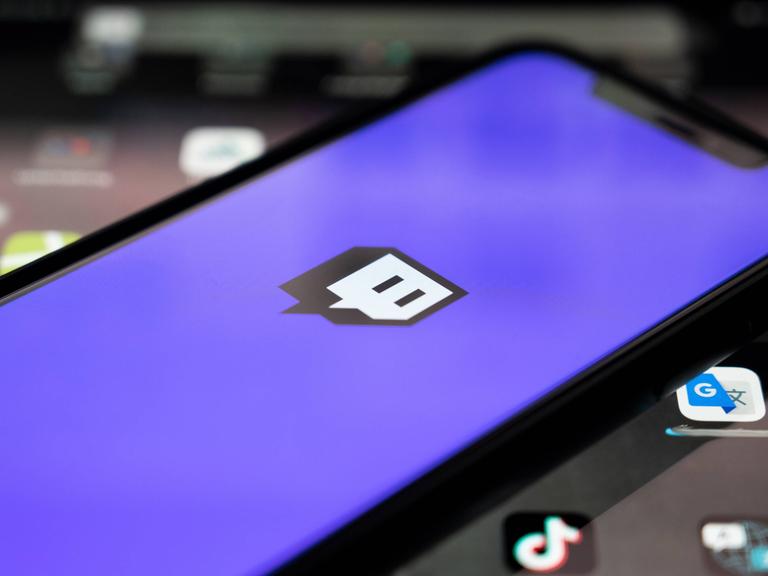 Blick auf ein Handy, auf dem Bildschirm ist das Twitch-Logo der App zu sehen Blick auf ein Handy, auf dem Bildschirm ist das Twitch-Logo der App zu sehen