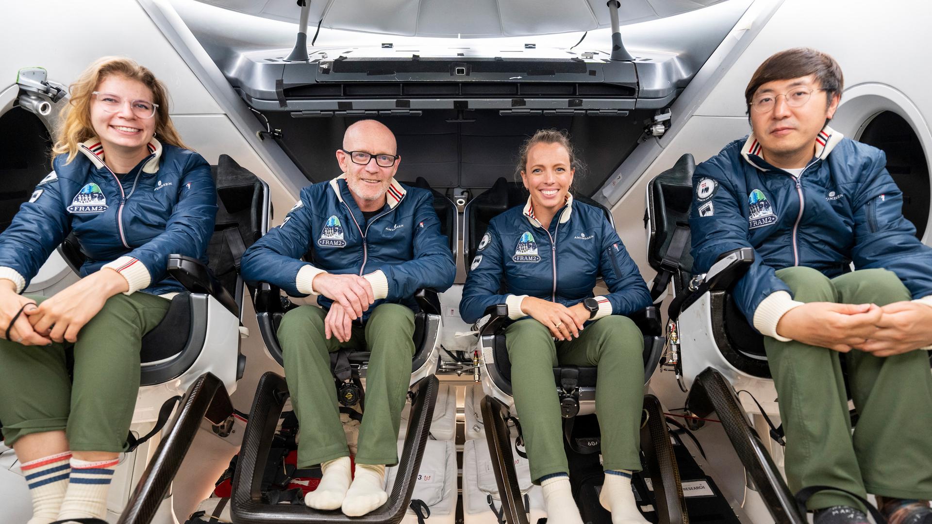 Vier Raumfahrer sitzen zur Übung ihrer Mission in einer Raumkapsel. Sie lächeln in Richtung der Kamera. Vier Raumfahrer sitzen zur Übung ihrer Mission in einer Raumkapsel. Sie lächeln in Richtung der Kamera.