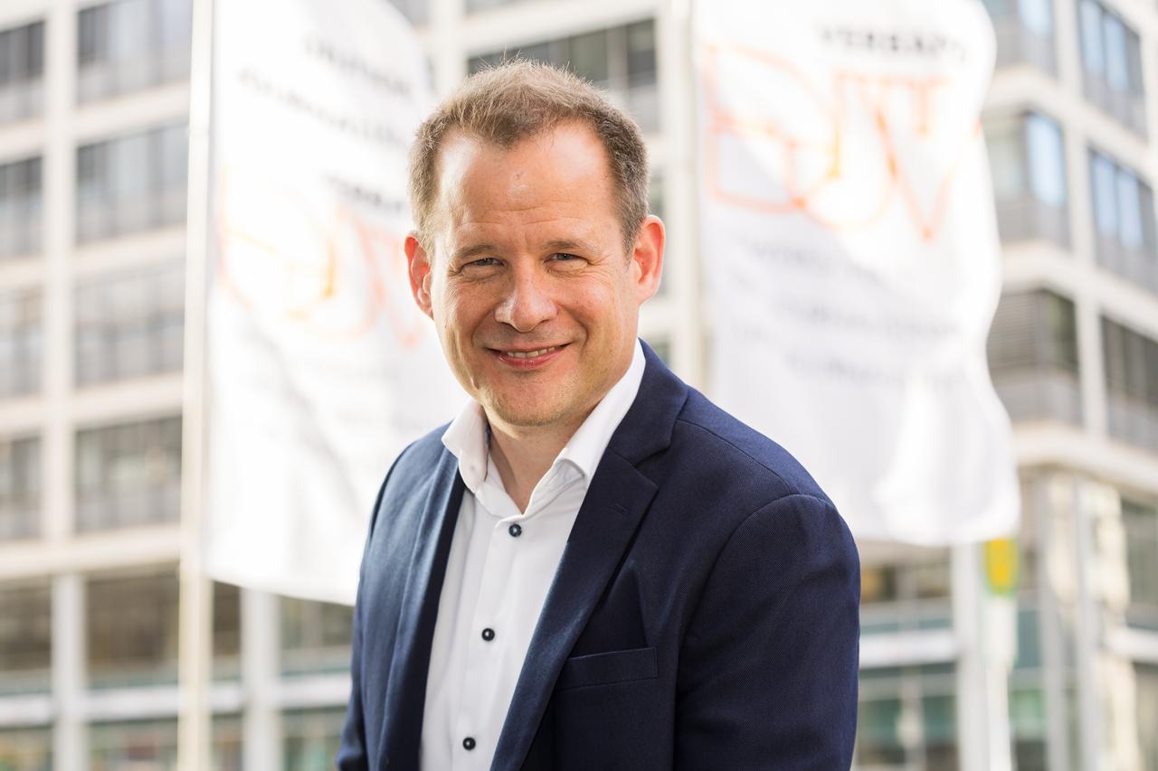 Mika Beuster steht vor Flaggen des DJV