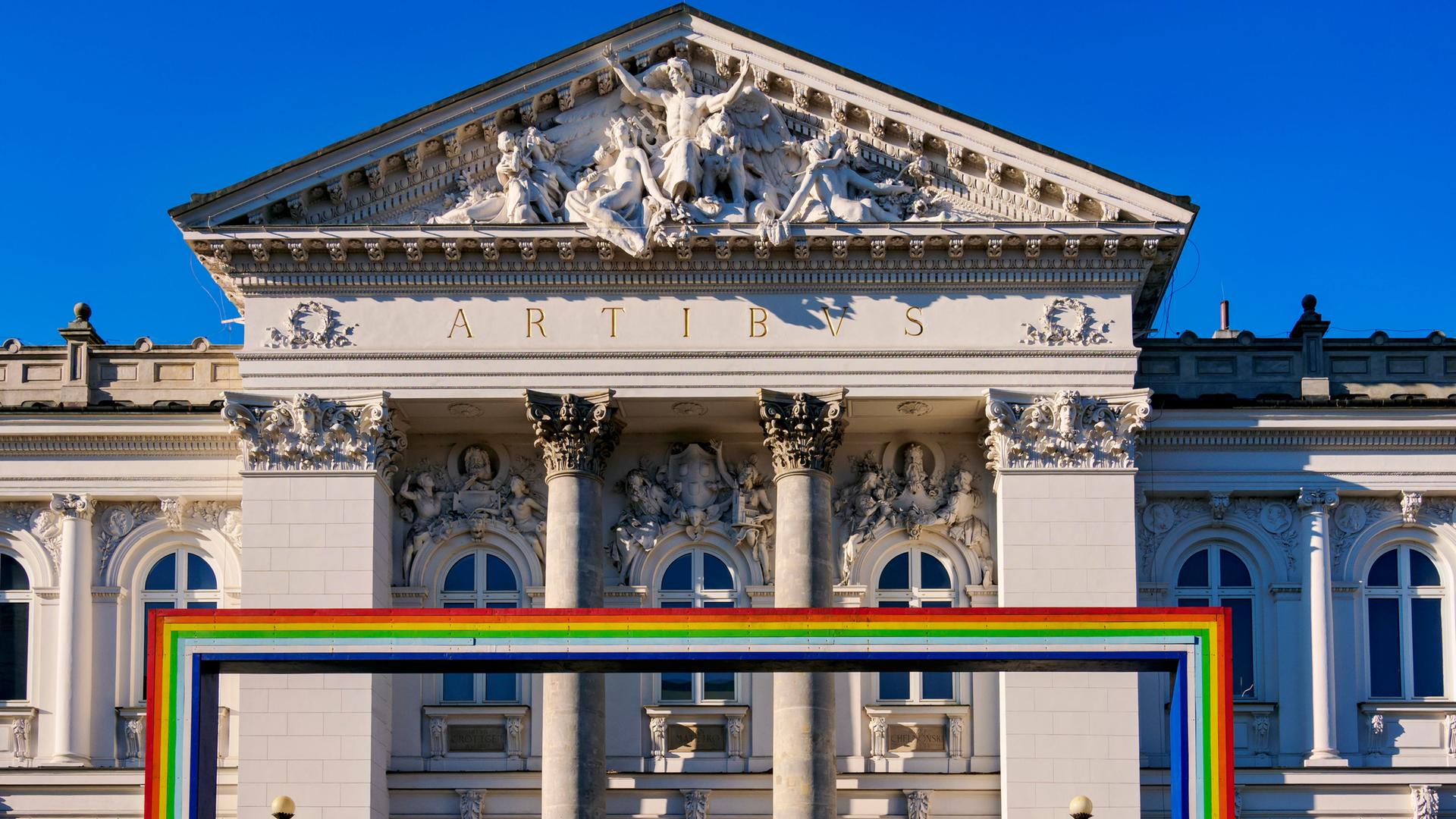 Symbolträchtiges Gebäude: Die Zachęta-Galerie in Warschau. Im Vordergrund ist ein Bogen aus den Farben des Regenbogens zu sehen, der für die LGBTQ-Community, also unter anderem Lesben und Schwule, steht.