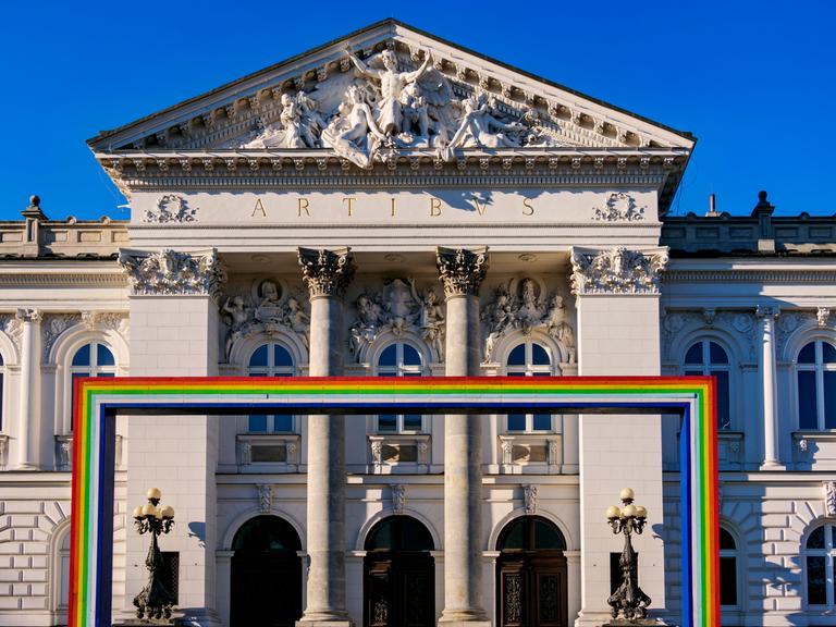 Symbolträchtiges Gebäude: Die Zachęta-Galerie in Warschau. Im Vordergrund ist ein Bogen aus den Farben des Regenbogens zu sehen, der für die LGBTQ-Community, also unter anderem Lesben und Schwule, steht.