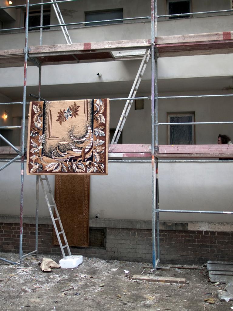 Ein Teppich hängt zum Trocknen auf einem Baustellengerüst in der Harzer Straße 65 in Berlin Neukölln. In dem Mehrfamilienhaus leben rund 400 Roma aus Rumänien. 