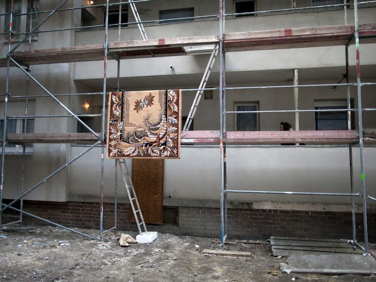 Ein Teppich hängt zum Trocknen auf einem Baustellengerüst in der Harzer Straße 65 in Berlin Neukölln. In dem Mehrfamilienhaus leben rund 400 Roma aus Rumänien. 