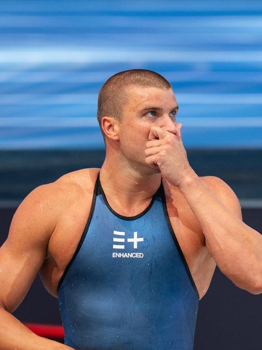 Der deutsche Schwimmer Marius Kusch steht am Beckenrand in blauer Schwimmbekleidung, die den Schriftzug der Enhanced Games trägt