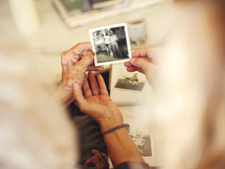 Hände, die alte Familienfotos halten