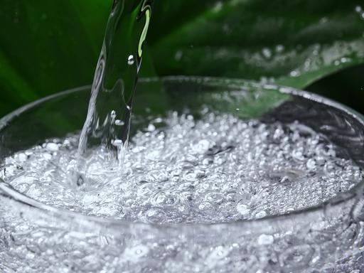 Mineralwasser mit Kohlensäure wird in ein Glas gegossen. 
