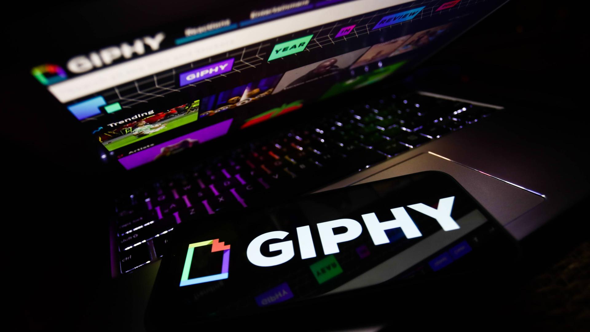 Ein Handy mit dem Giphy-Logo liegt auf einem Laptop, auf dem Giphy aufgerufen ist.