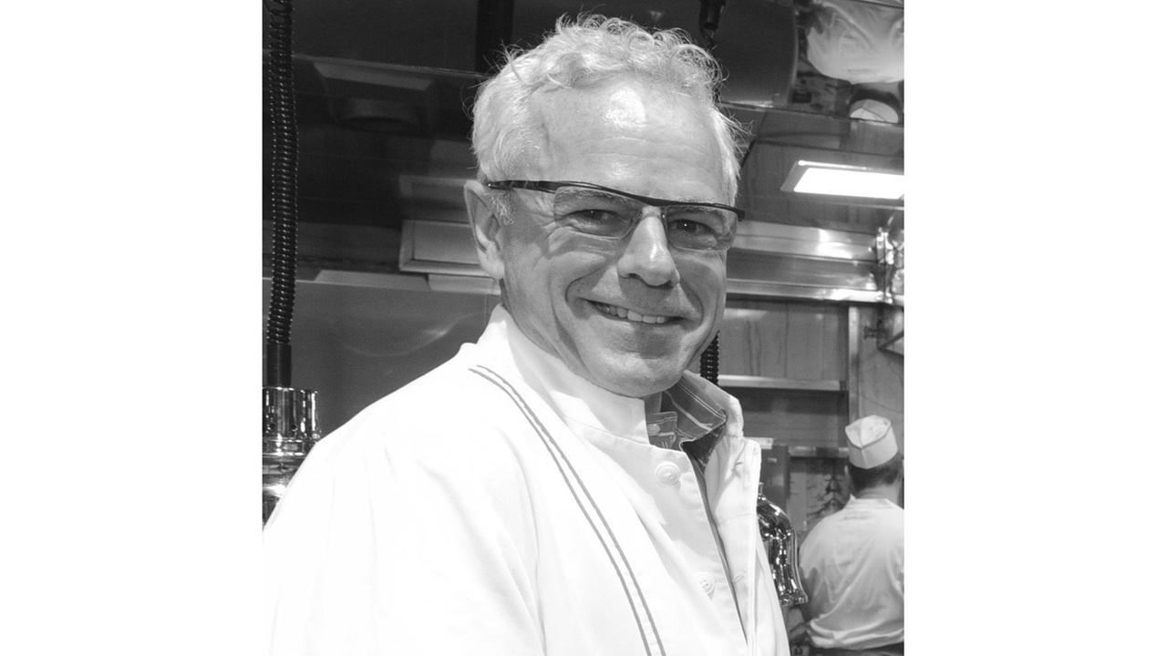 USA, New York: Sternekoch David Bouley steht in einer Küche und lächelt in die Kamera.