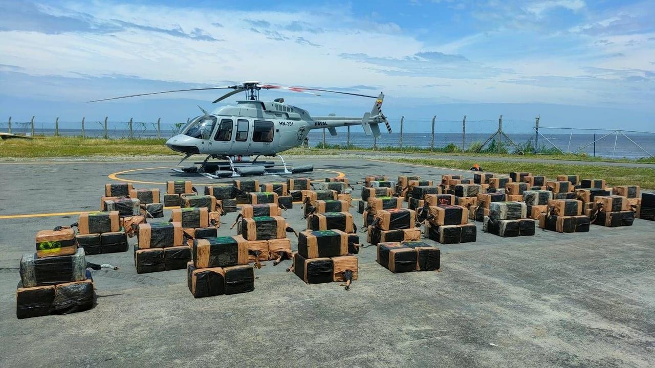 Ecuador: Viereckige Verpackungen mit sichergestelltem Kokain liegen nebeneinander. Dahinter ein Hubschrauber.
