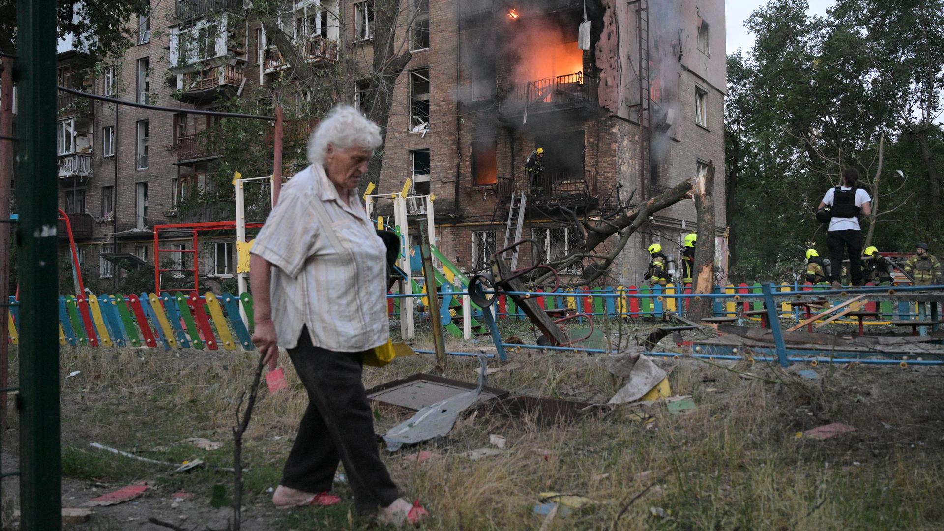 Ukraine, Kiew: Eine Frau geht nach einem russischen Angriff an einem brennenden Wohnhaus vorbei. Ukraine, Kiew: Eine Frau geht nach einem russischen Angriff an einem brennenden Wohnhaus vorbei.