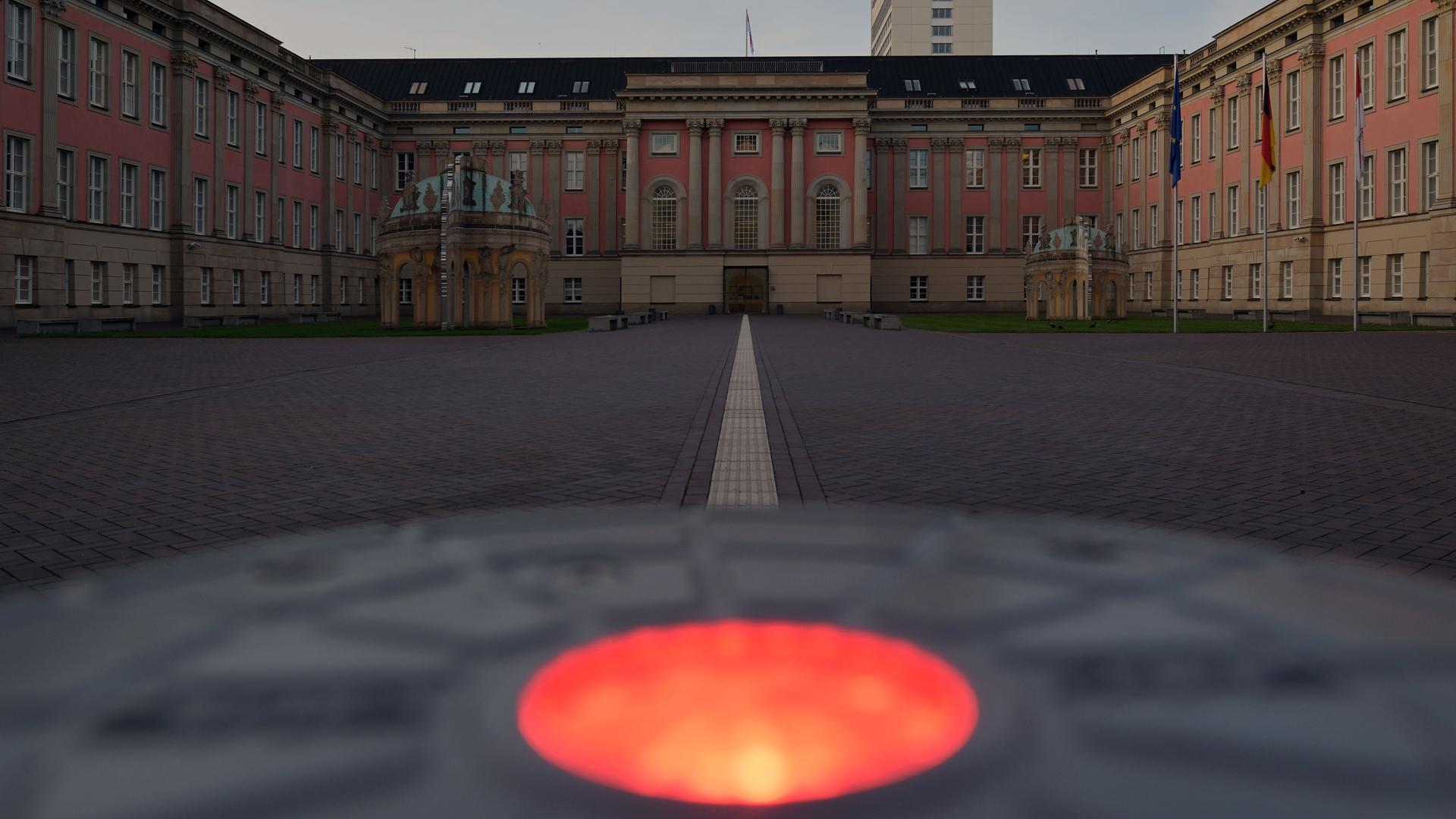 Der Eingang des Brandenburger Landtags im Morgengrauen. Im Vordergrund leuchtet ein rotes Licht auf einem versenkbaren Absperrpoller.