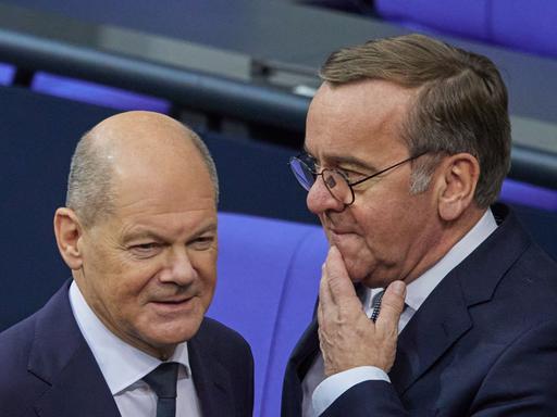 Bundeskanzler Olaf Scholz (l, SPD) und Boris Pistorius (SPD), stehen nebeneinander im Bundestag, schauen aber in unterschiedliche Richtungen.