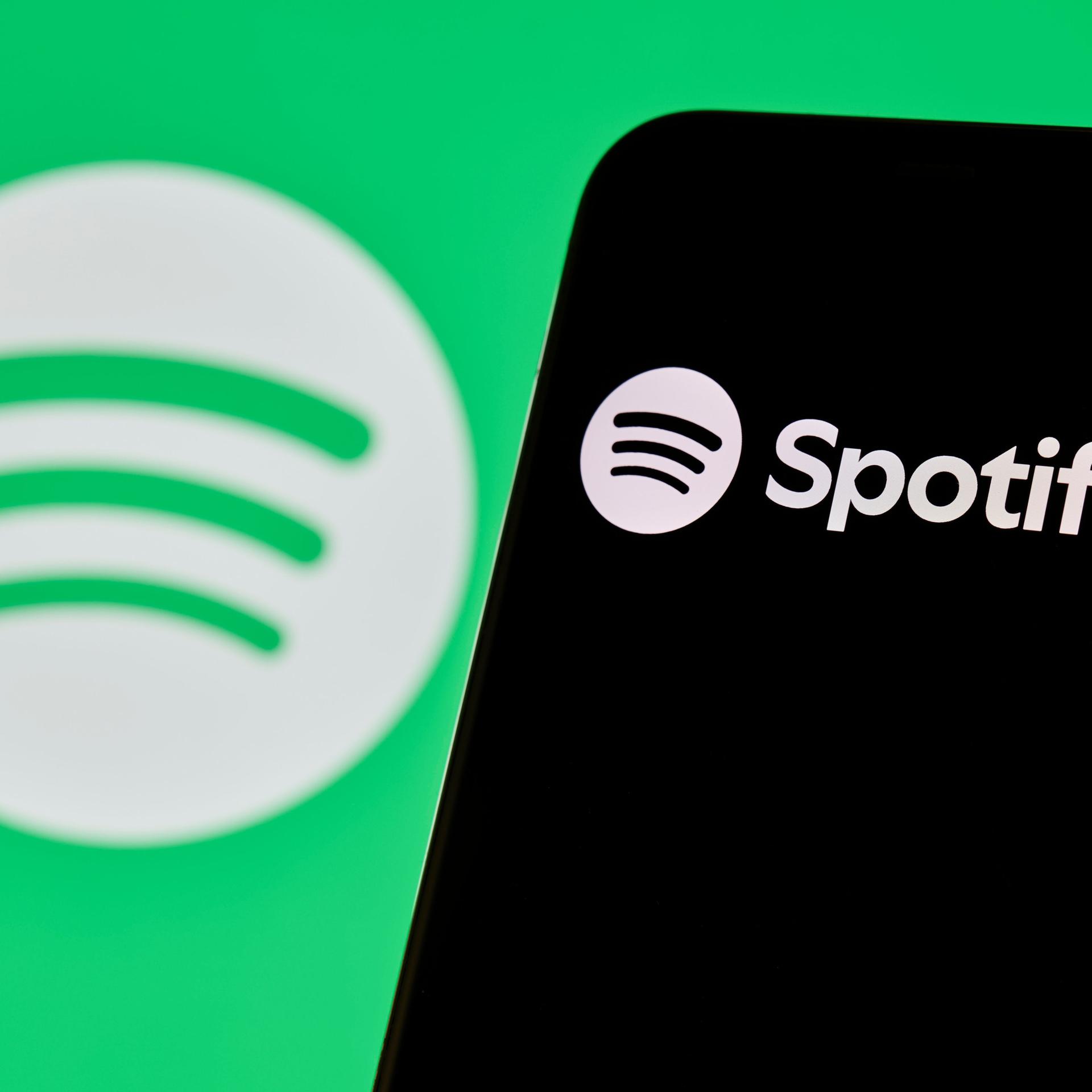 Spotify-Logo und App-Oberfläche auf dem Smartphone-Bildschirm angezeigt.