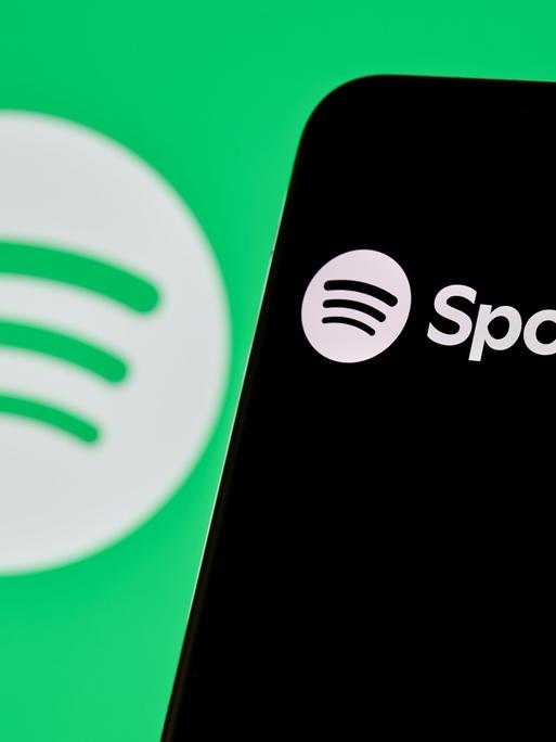 Spotify-Logo und App-Oberfläche auf dem Smartphone-Bildschirm angezeigt.