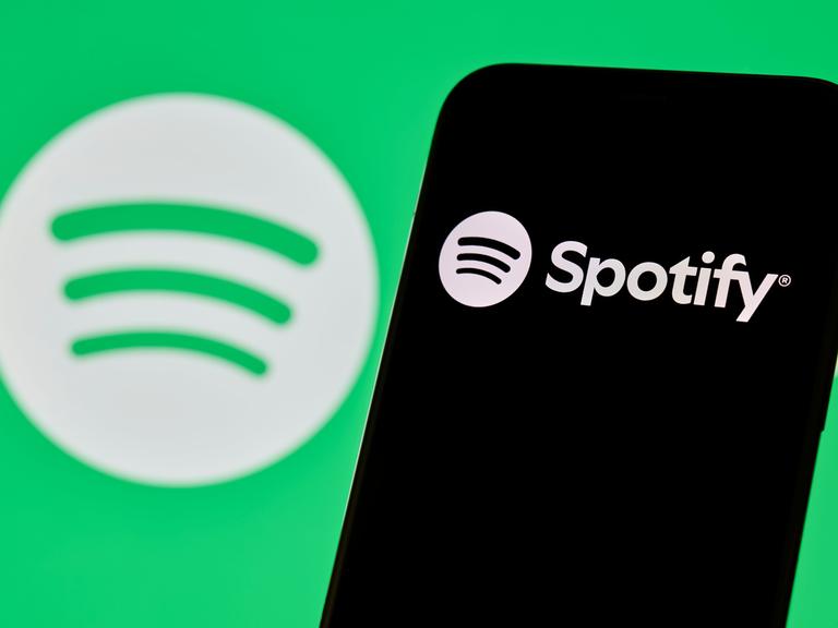Spotify-Logo und App-Oberfläche auf dem Smartphone-Bildschirm angezeigt.