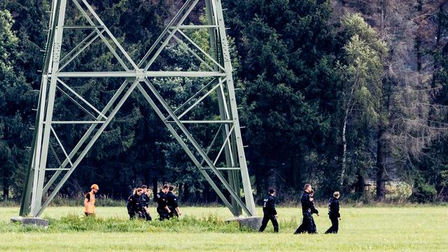Einsatzkräfte einer Polizeihundertschaft laufen im Gebiet um das Umspannwerk Turnow-Preilack und das Kraftwerk Jänschwalde an einem Strommast vorbei. 