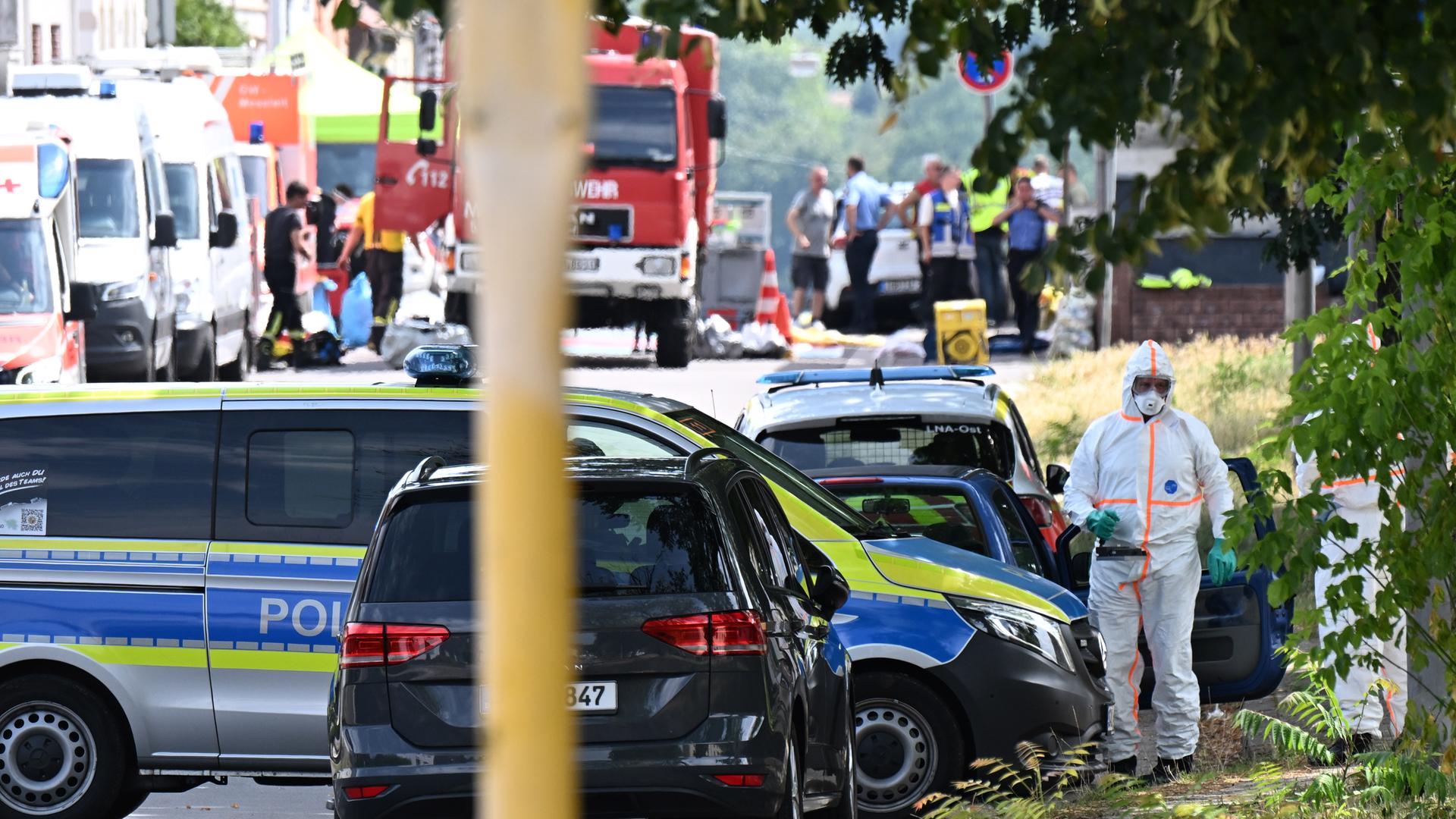 Saarland, Sankt Ingbert: Einsatzkräfte untersuchen ein Auto auf Radioaktivität. Im Hintergrund sind mehrere Rettungswagen und Polizeifahrzeuge. 